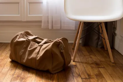 Packed canvas duffel bag on a wooden floor ready for a trip
