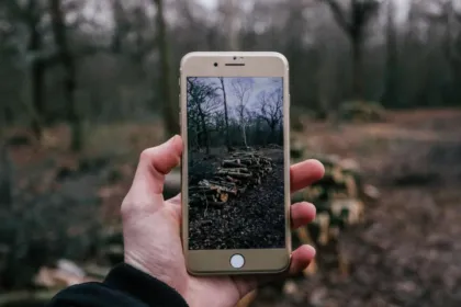 Hand holding a smartphone in a forest, a reminder to reduce screen time and look up