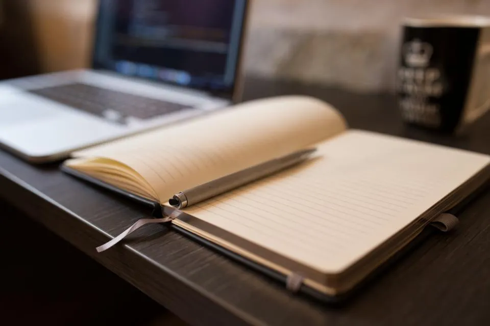Open notebook and pen beside a laptop, ready for writing a simple business plan