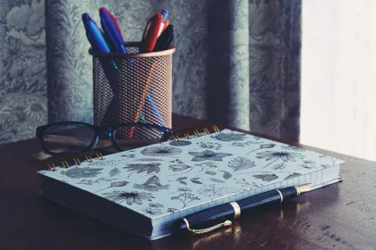 Notebook, fountain pen, glasses and pens on a study desk