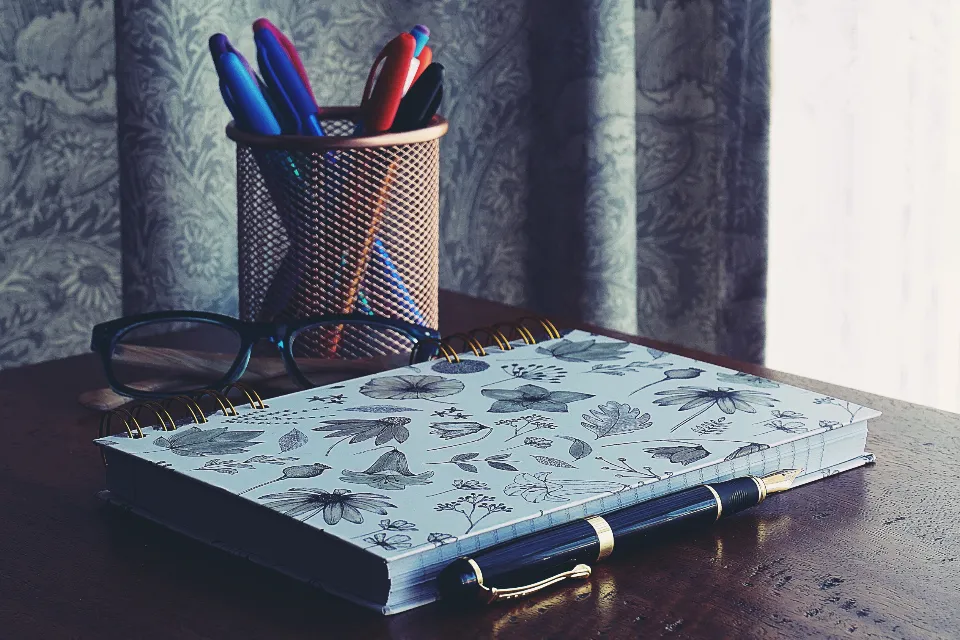 Notebook, fountain pen, glasses and pens on a study desk