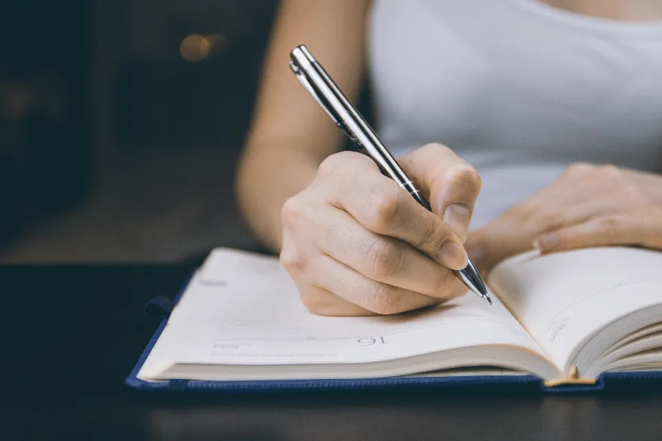 Professional writing a time-blocked schedule in a paper planner