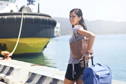Smiling traveler with a small bag at a harbor abroad